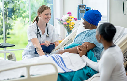 Nurse smiling warmly at a patient lying on the bed, conveying care and compassion through their interaction.